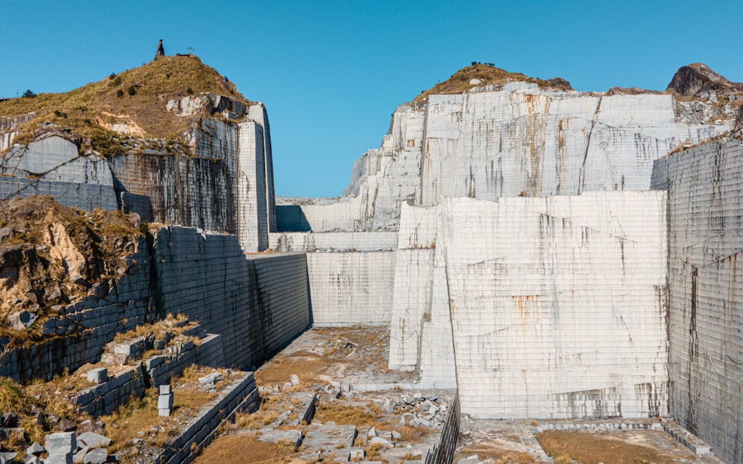 Stone quarry hillside viewed behind a metal safety fence